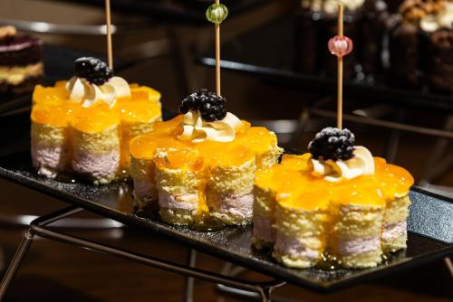 a group of cakes with blackberries on top on a tray at Razana Al Rawdha Hotel in Makkah