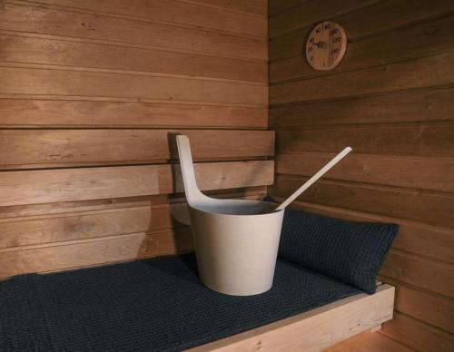 ein Eimer in einer Ecke einer Sauna mit einer Uhr in der Unterkunft Premium Apartment With Sauna & Parking - Lapnest in Rovaniemi