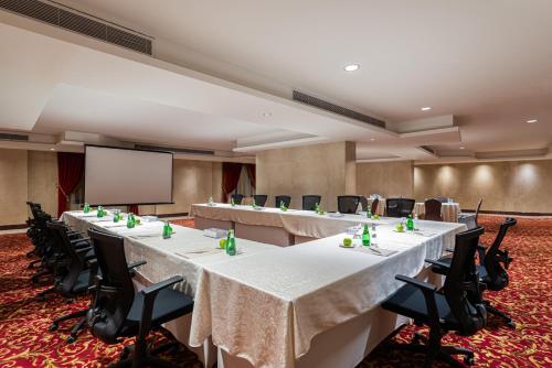 a conference room with tables and chairs and a screen at Razana Al Rawdha Hotel in Makkah