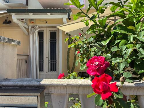 ein Haus mit roten Blumen auf einem Steinzaun in der Unterkunft Piano terra con giardino, vicino al mare in Viareggio