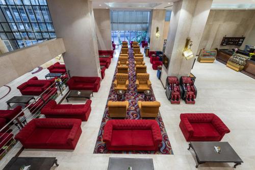 an empty waiting room with red chairs and tables at Razana Al Rawdha Hotel in Makkah
