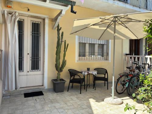 eine Terrasse mit Tisch und Stühlen und einem Sonnenschirm in der Unterkunft Piano terra con giardino, vicino al mare in Viareggio
