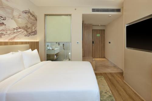 a bedroom with a large white bed and a flat screen tv at Riviera Sarovar Portico Pathankot in Pathānkot