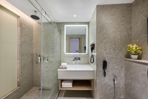 a bathroom with a sink and a glass shower at Riviera Sarovar Portico Pathankot in Pathānkot