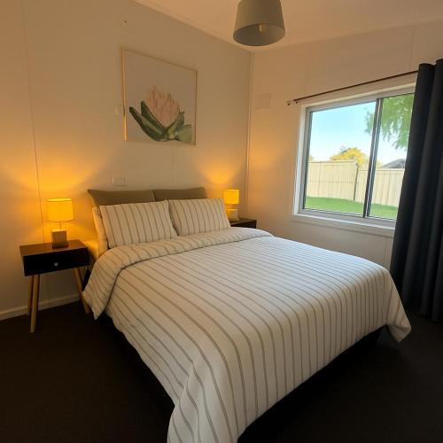a bedroom with a bed with two lamps and a window at Longford Cottage in Longford