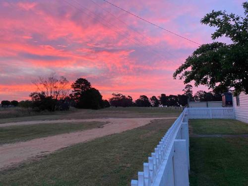a sunset over a field with a white fence at Longford Cottage in Longford