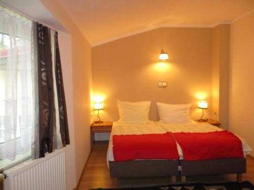 sypialnia z łóżkiem z czerwono-białym kocem w obiekcie Hotel Pod Platanami w mieście Trzebnica
