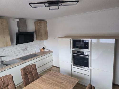 a kitchen with white appliances and a wooden table at Apartment Bergblick Bad Berleburg in Bad Berleburg