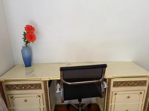 a desk with a vase of flowers and a chair at The Good Spot In Glen Waverley in Glen Waverley
