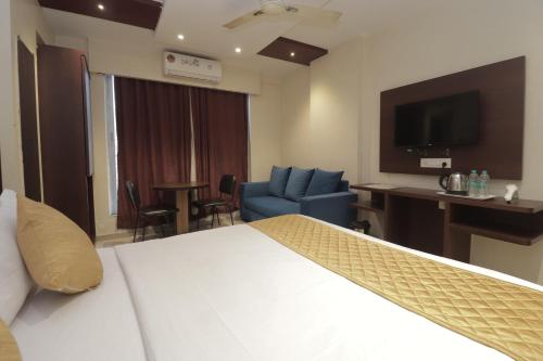 a hotel room with a bed and a chair and a television at Hotel Malad Inn opposite Malad Railway Station in Mumbai