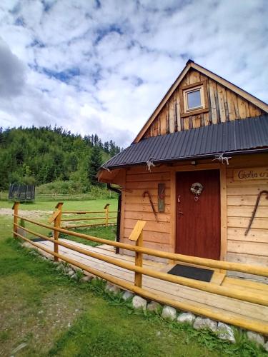 a wooden cabin with a fence in a field at Chatka w Dolinie in Witów