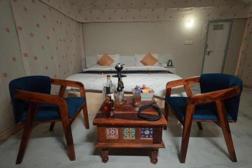a bedroom with a bed and two chairs and a table at Arman Desert Luxury Camp & Resort Jaisalmer in Jaisalmer