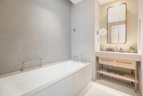 ein weißes Bad mit einer Badewanne und einem Spiegel in der Unterkunft Vida Dubai Mall Balcony with Burj & City Views walk to Dubai Mall by Heaven Crest Vacation Homes in Dubai