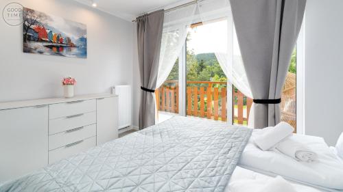 Un dormitorio blanco con una cama y una ventana. en Apartamenty Good Time - Z widokiem na góry, en Szklarska Poręba