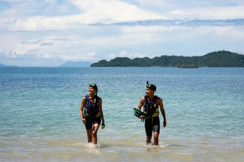 two people walking in the water on the beach at Lampung Marriott Resort & Spa in Lampung