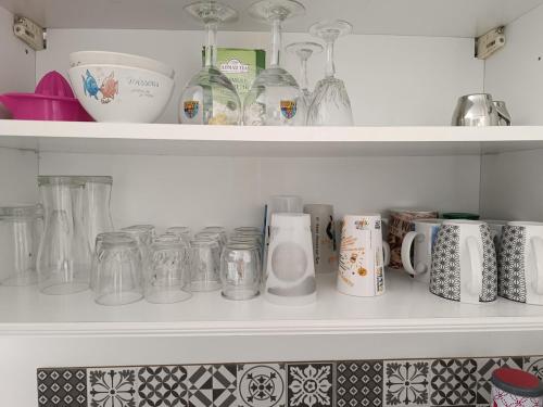 a shelf full of glass jars and mugs at Charmante petite maison à la campagne in Soulanges