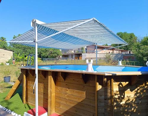 an umbrella over a swimming pool in a yard at Charmante petite maison à la campagne in Soulanges