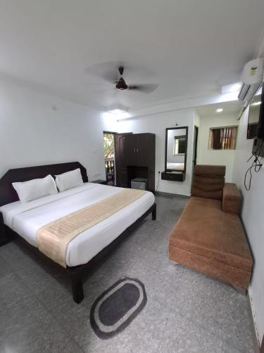 a bedroom with a large bed and a chair at Raj Resort Calangute in Calangute