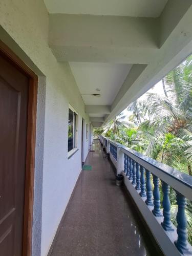 a corridor of a building with a balcony with palm trees at Raj Resort Calangute in Calangute