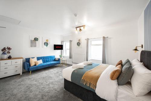 ein Schlafzimmer mit einem Bett und einer blauen Couch in der Unterkunft Aurum House Luxury Apartments in Blackpool