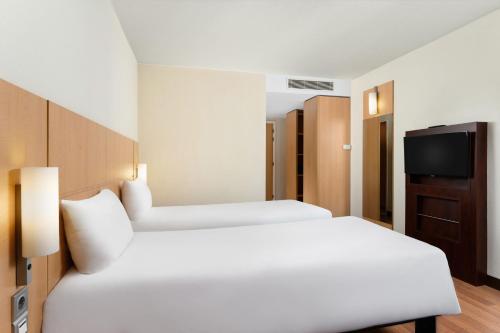 a hotel room with two beds and a television at Ibis Budapest Heroes Square in Budapest