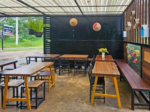 a group of tables and benches in a restaurant at Norn nee Na Hostel นอน นี่ นะ โฮสเทล in Ban Non Na Yao