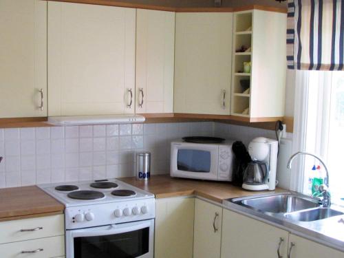 a kitchen with a stove and a microwave at 6 person holiday home in LJUNG-By Traum in Alboga