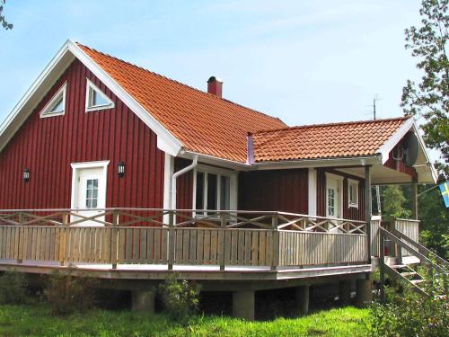 a red house with a large deck in front of it at 6 person holiday home in LJUNG-By Traum in Alboga