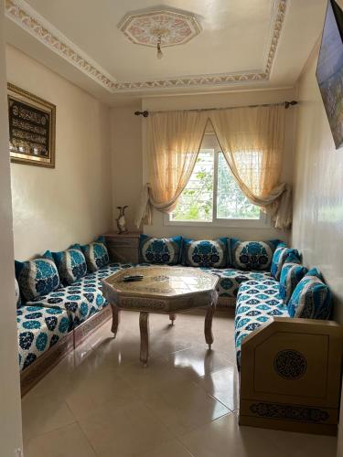 a living room with couches and a table and a window at شقة مفروشة بالقصر الكبير in Ksar el Kebir