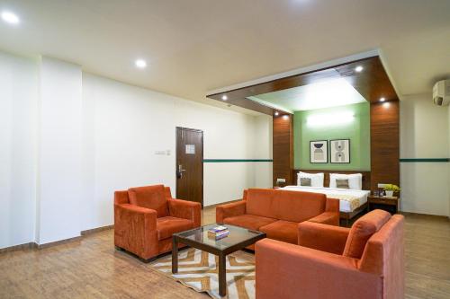 a living room with two chairs and a bed at Olive Hotel Electronic City by Embassy Group in Bengaluru