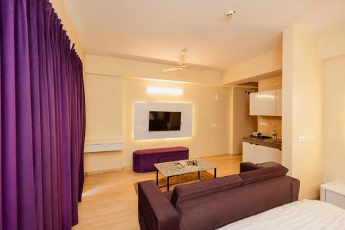 a living room with purple curtains and a couch at Skystay Lucknow in Lucknow