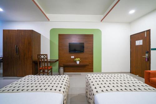 a room with two beds and a tv on a wall at Olive Hotel Electronic City by Embassy Group in Bengaluru