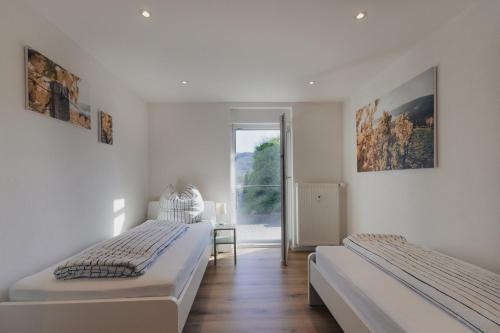 two beds in a white room with a window at Bürgstadt, Am Bischof mit Sonnenterrasse, 1 bis 4 Betten in Buergstadt