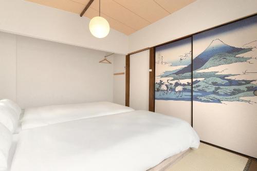 a bedroom with a white bed and a painting at YokaYado Kagoshima Chuo - Retro Style Japanese Modern Entire House with Rooftop Balcony in Kagoshima