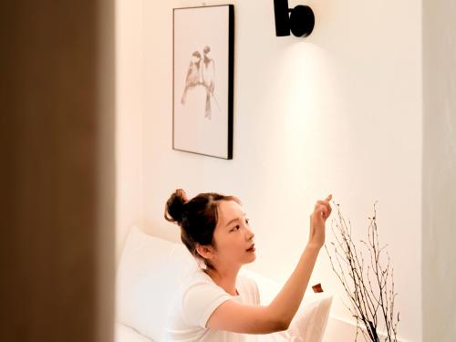 a woman sitting on a bed looking at a wall at Stay 42 Dongmyo in Seoul