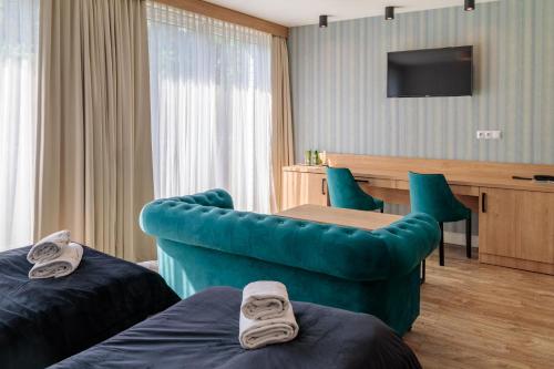 a hotel room with a blue couch and a desk at Luksusowe Apartamenty Echo in Cedzyna