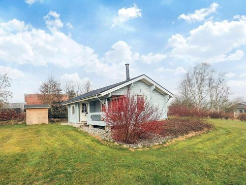 a small white house with a red bush in front of it at 6 person holiday home in Roslev-By Traum in Flovtrup