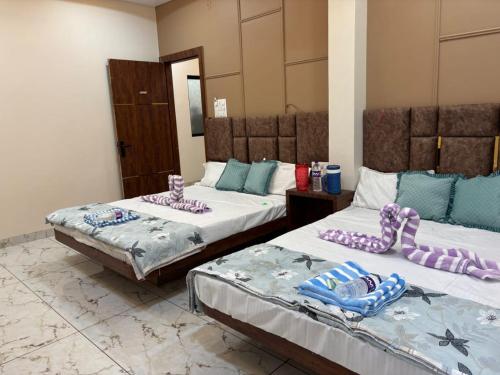 two beds in a room with purple and blue pillows at Hotel shree Gajanand palace in Ujjain