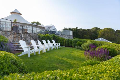 a row of white chairs sitting in a garden at Wequassett Resort and Golf Club in East Harwich