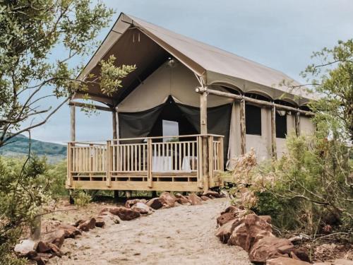 a tent with a porch in the middle of a field at Matatane Camp - Babanango Game Reserve in Nkwalini