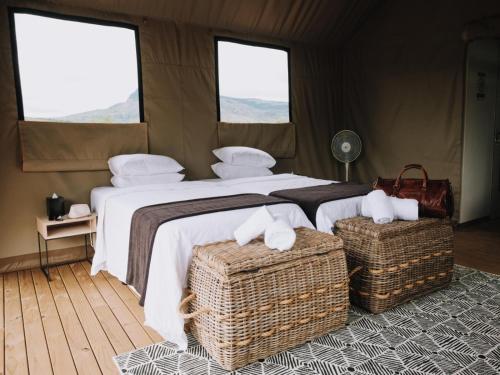 a bedroom with a large bed and two windows at Matatane Camp - Babanango Game Reserve in Nkwalini