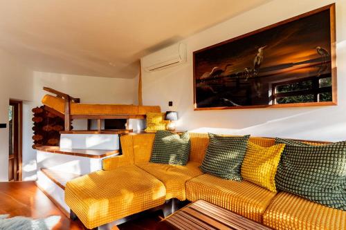 a living room with a yellow couch with green pillows at Farkaskútvölgy in Felsőtold