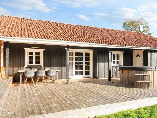 グレーノにある7 person holiday home in Grenaaのデッキにテーブルと椅子が備わる家