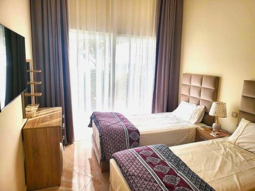 a hotel room with two beds and a window at Superbe appartement à bouznika avec vue sur piscine et jardin privatif in Bouznika