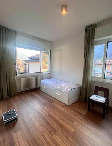 a bedroom with a bed and two windows at Jade Valbrona Apartment in Valbrona