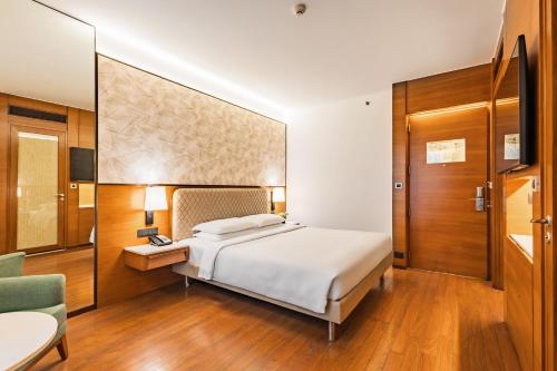 a hotel room with a bed and a chair and a television at Hyatt Pune in Pune
