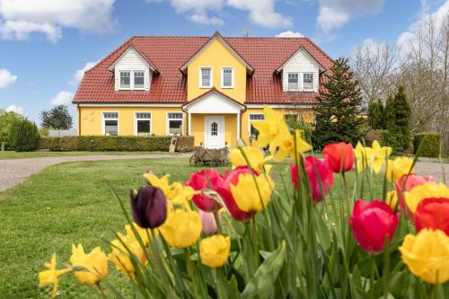 a yellow house with flowers in front of it at Ferienhof am Leuchtturm mit Meerbl in Kägsdorf