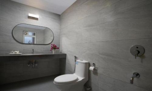 a bathroom with a toilet and a sink and a mirror at Paprika Stays Panjim Donapaula in Panaji