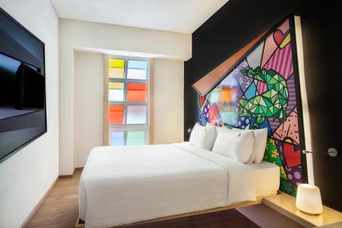 a bedroom with a white bed with a stained glass window at MaxOneHotel Tidar Surabaya in Surabaya