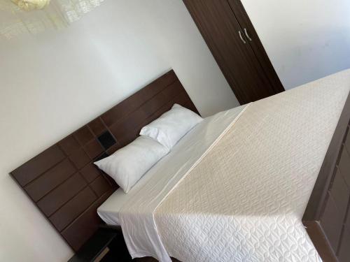 una cama con cabecero de madera y dos almohadas en Roots Recreational Center, en Kabale